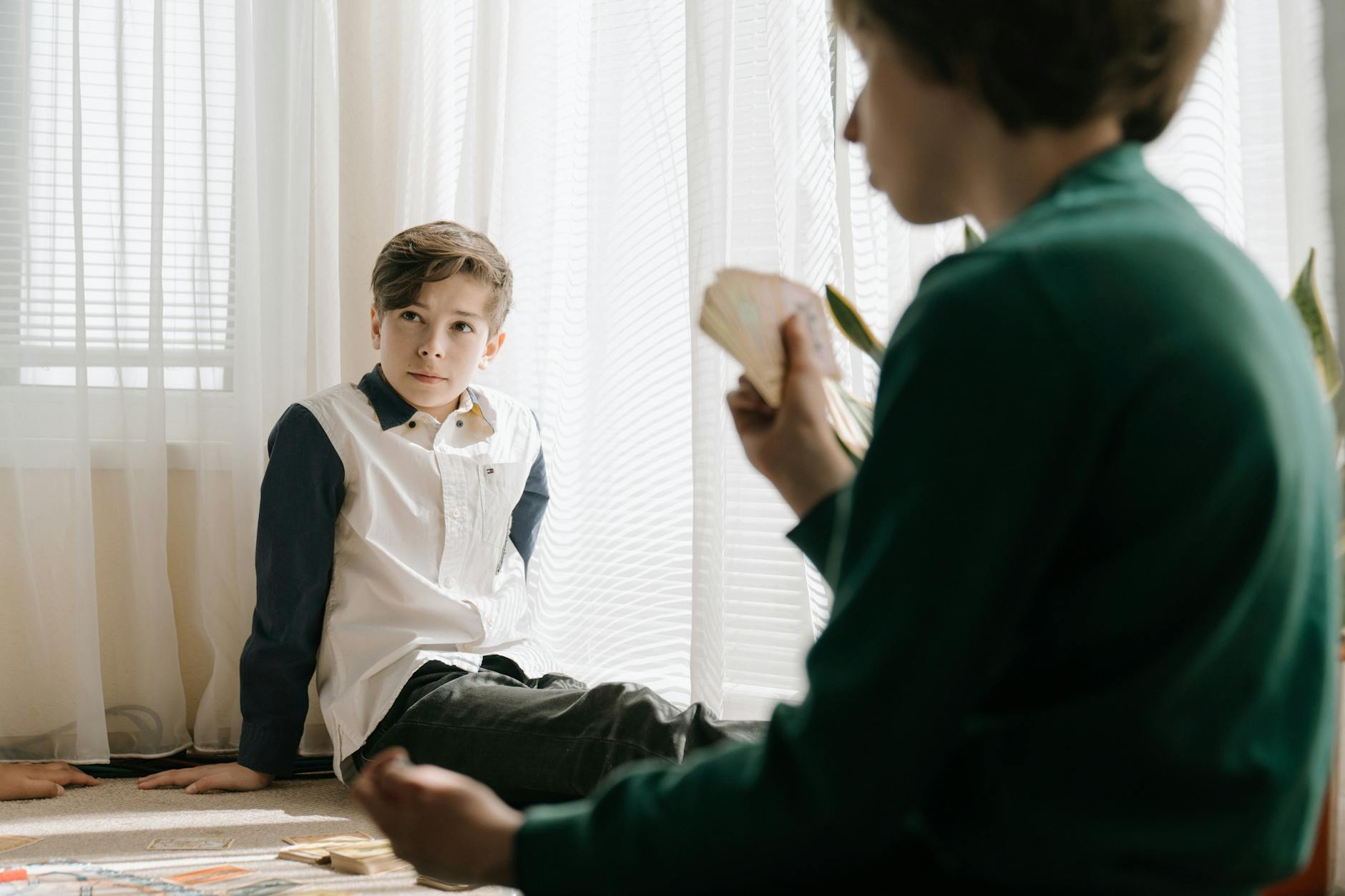 Dwoje dzieci gra w karty przy stole w domu